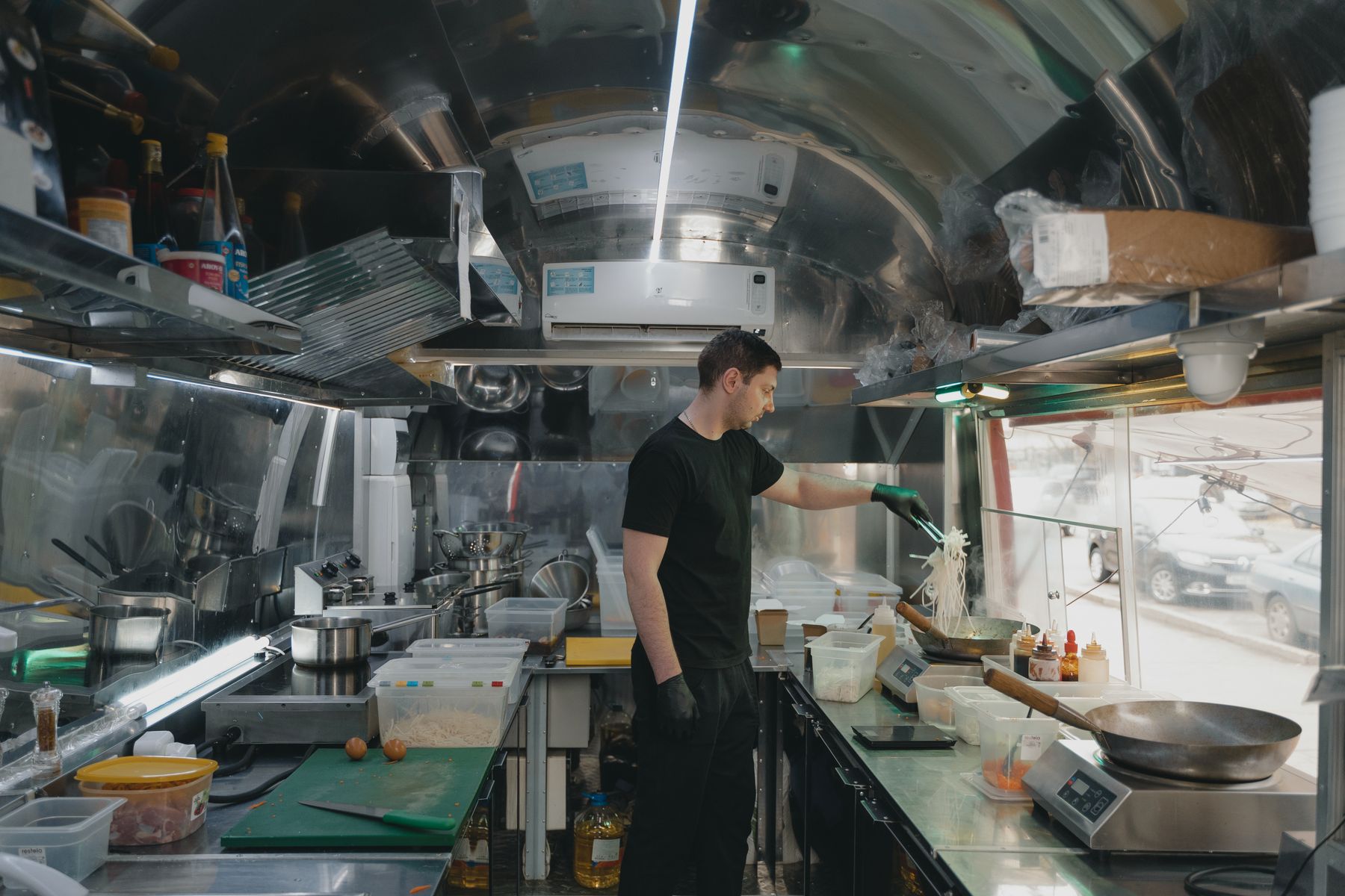 Cook working at the service window inside a stainless-steel food truck